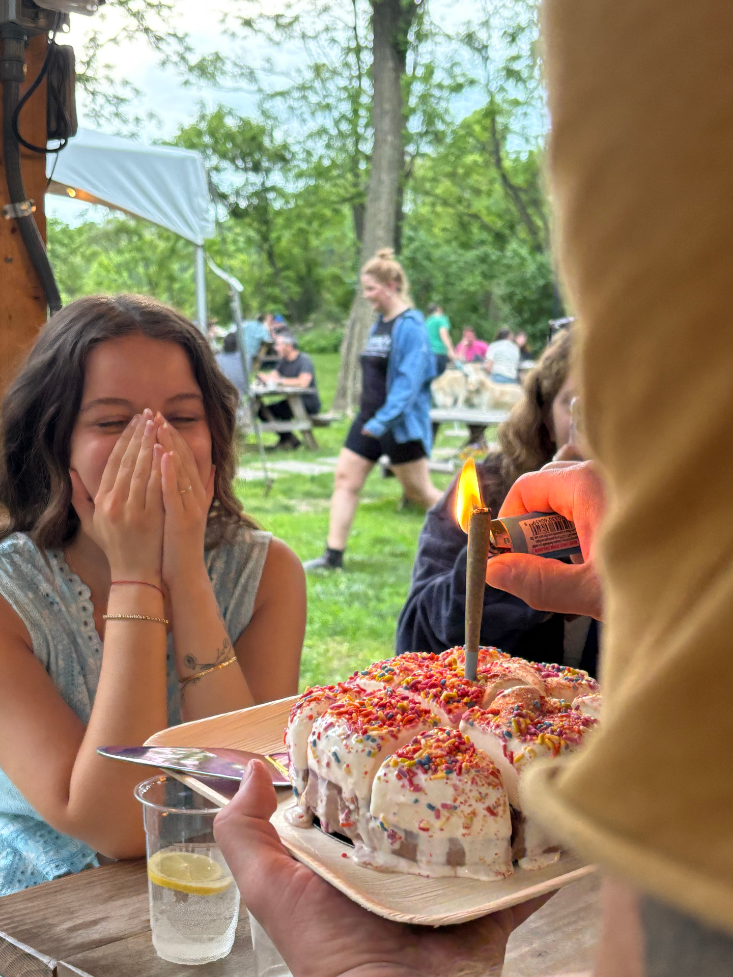 Noa laughing behind her hands as the cake arrives