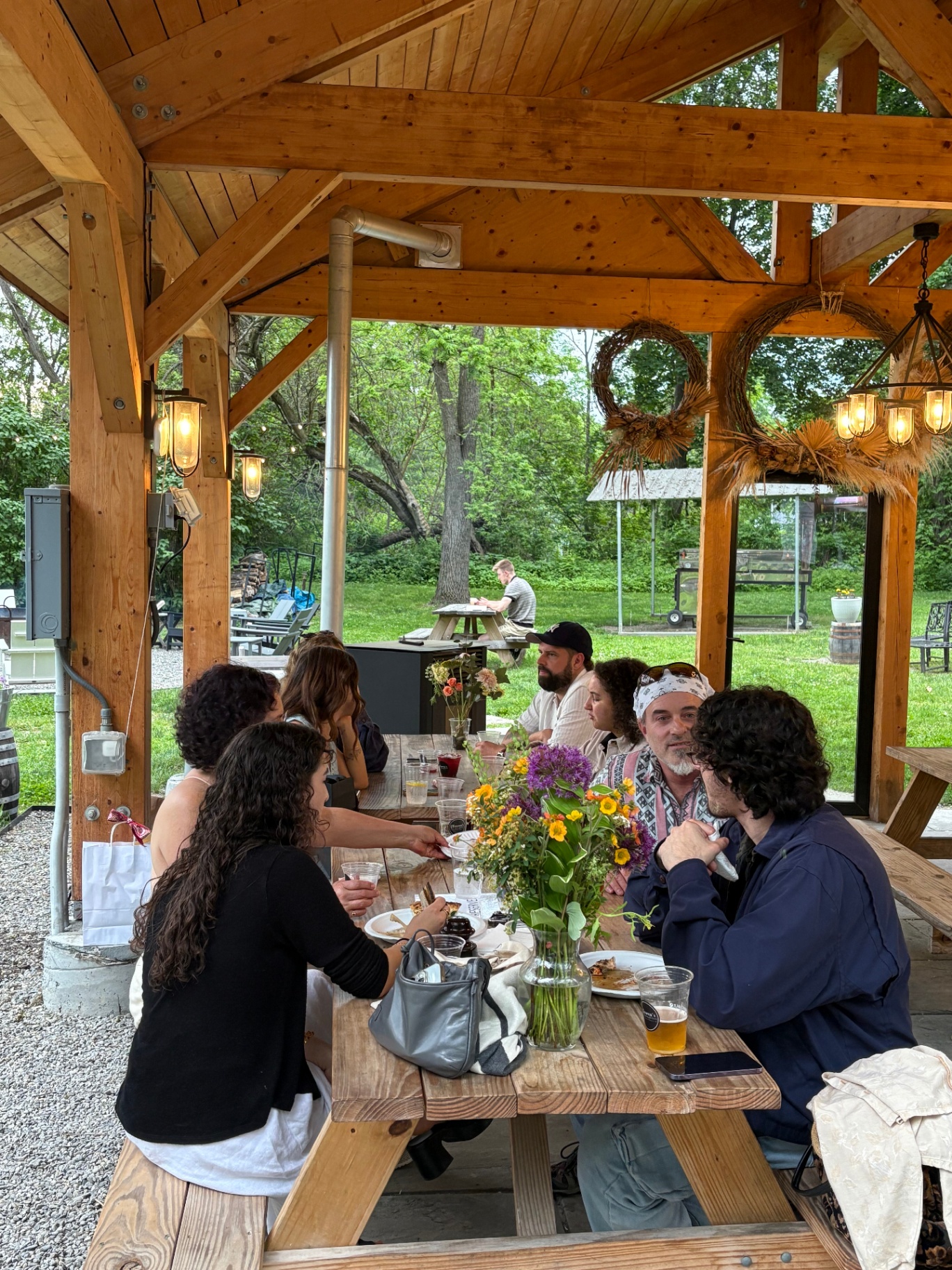 Friends and family sharing a meal under a wooden pavilion
