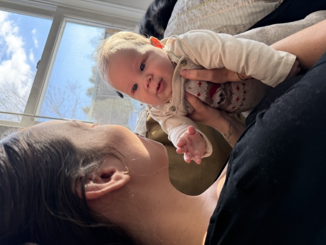 Noa holding Oren by a bright window